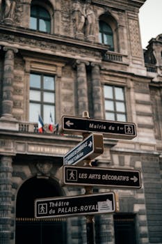 Street view capturing classic Parisian architecture and directional signs in Paris, France.