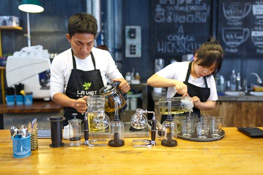 Two baristas are actively preparing beverages in a lively coffee shop setting.